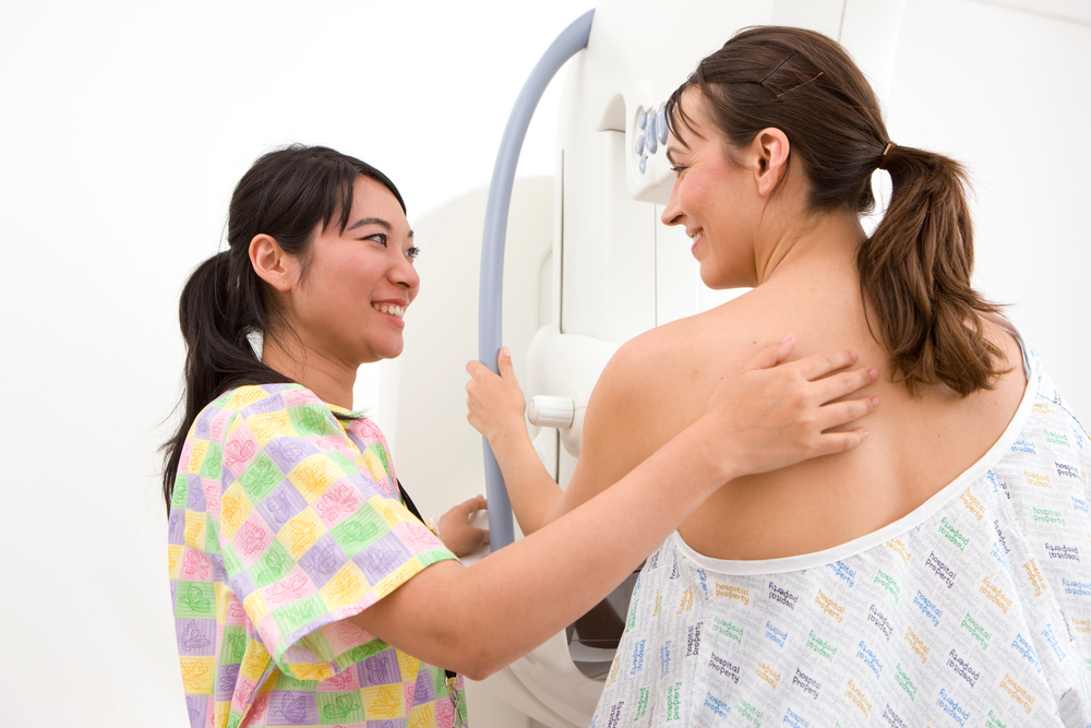 A candid shot of professional radiologist happily attending a patient on a mammogram machine