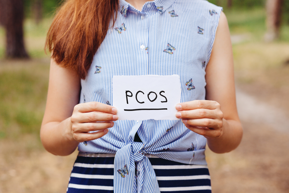 woman holding paper with pcos written on it