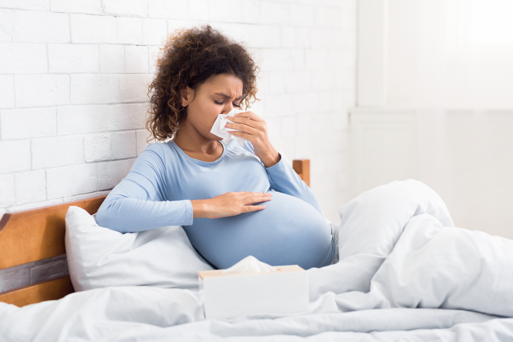 Pregnant woman blowing nose.