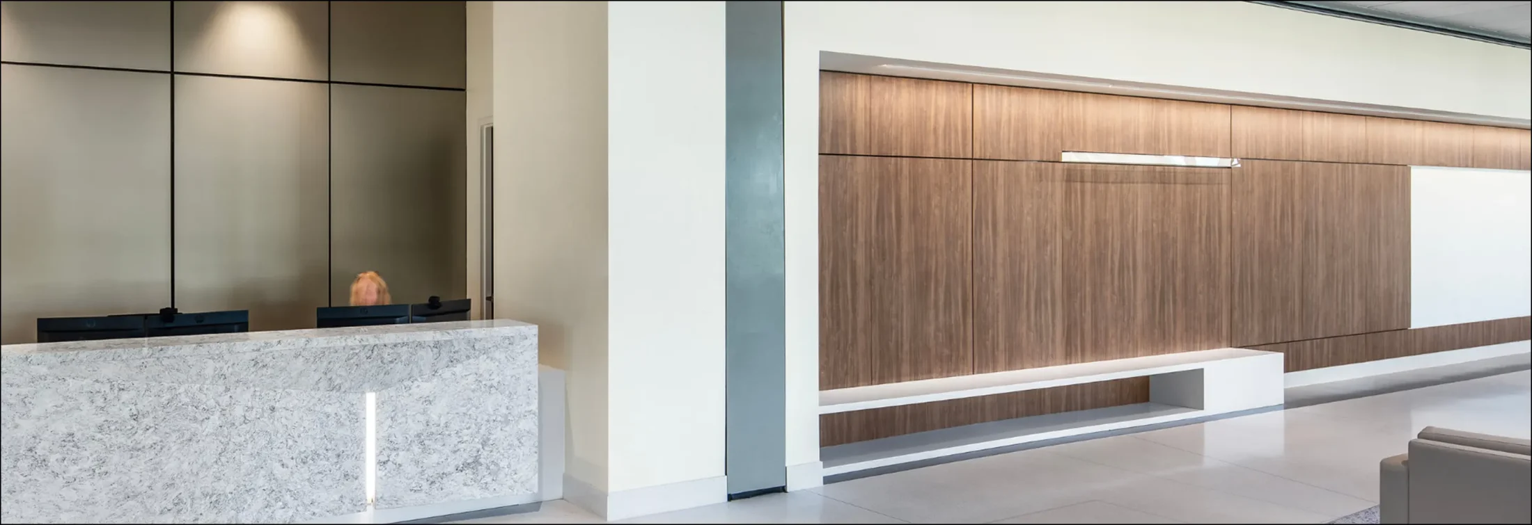 Modern medical office reception area featuring a marble desk and elegant wood-paneled walls.