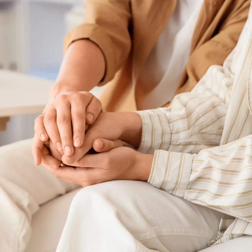 Close-up of hands holding each other in a supportive and comforting gesture.