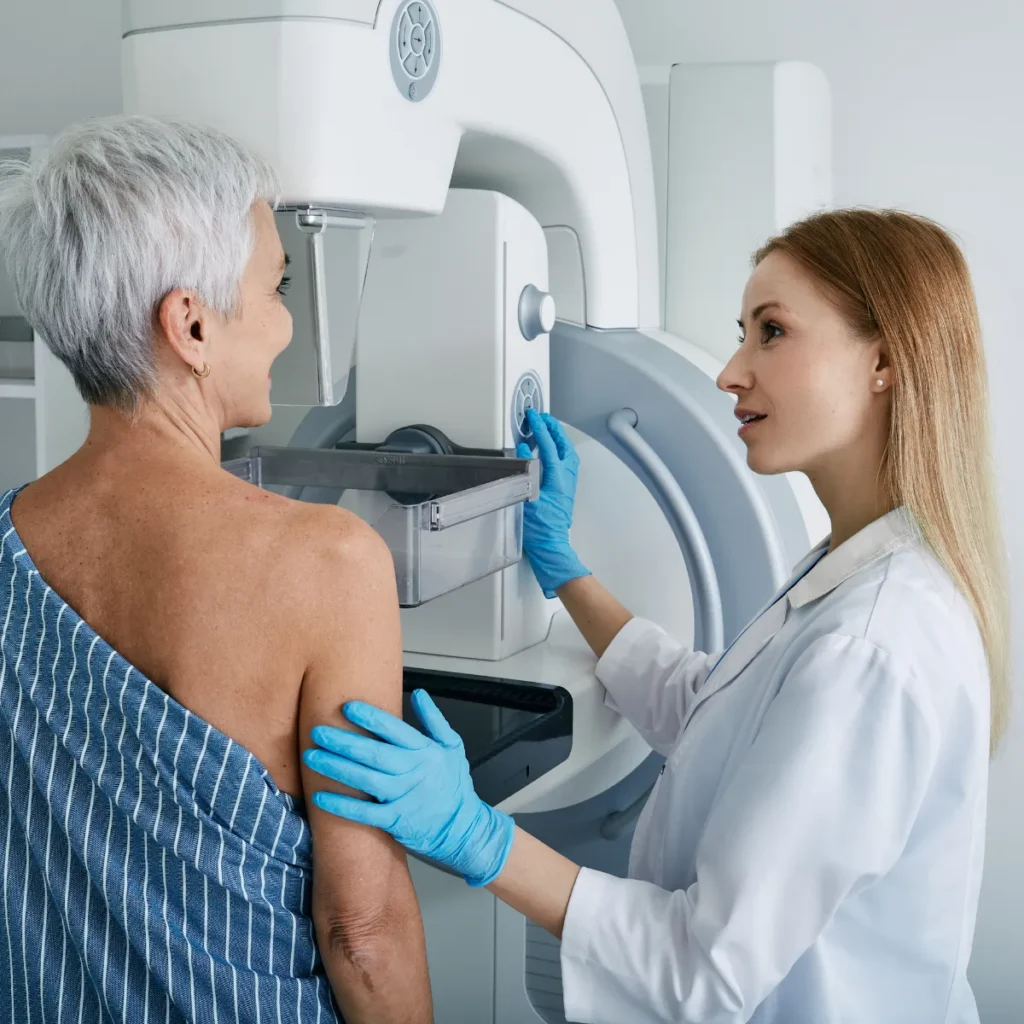 A healthcare provider assists a senior patient during a mammogram screening.