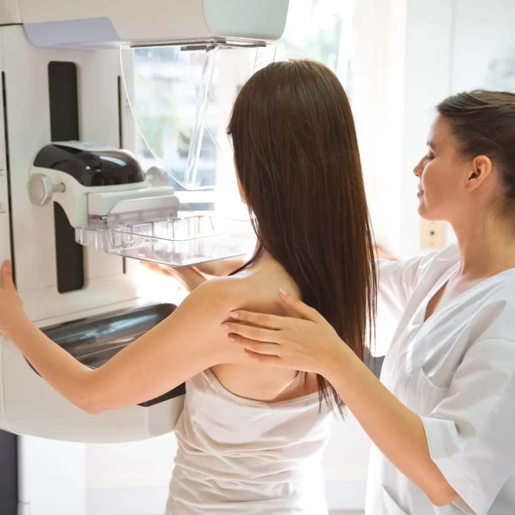 A healthcare provider assists a patient during a mammogram screening.