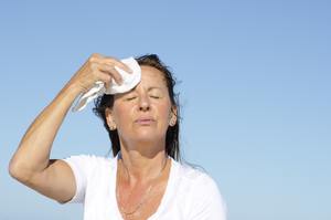 woman wiping sweat off her face with towel
