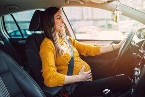 pregnant woman driving her car.