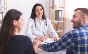 couple holding hands and smiling talking to doctor