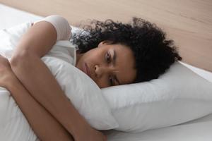 woman sad laying in bed