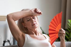 woman fanning herself due to menopause hot flashes