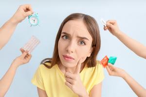 houghtful young woman and hands with different means of contraception on color background