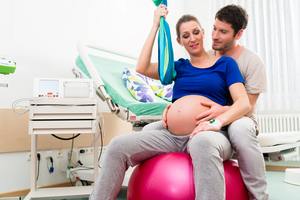 woman on ball in hospital room with husband