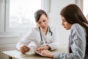 Young woman talking with woman doctor